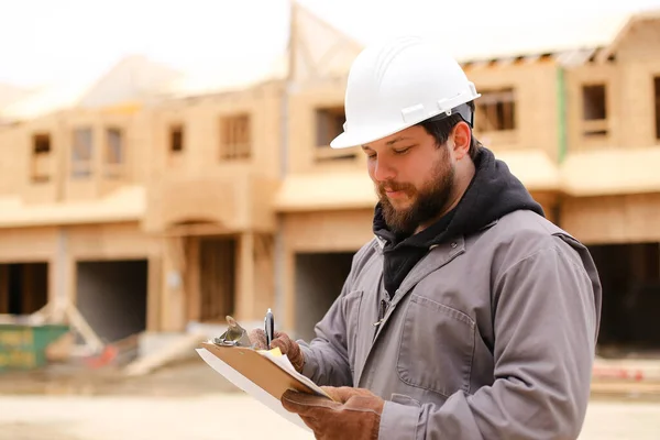 Caucasian engineer drawing plan in notebook at construction site.