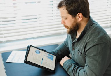 Ofisteki tablette grafik ve diyagramlarla çalışan mühendis.