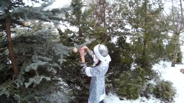 Snow Maiden στο δάσος κρεμαστά παιχνίδια σε ένα σταθερό δέντρο χαμογελώντας scene2 Ουκρανίας — Αρχείο Βίντεο