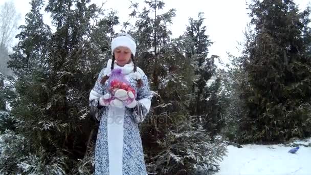 Schneemädchen im Wald überreicht Geschenk vor Kiefer — Stockvideo