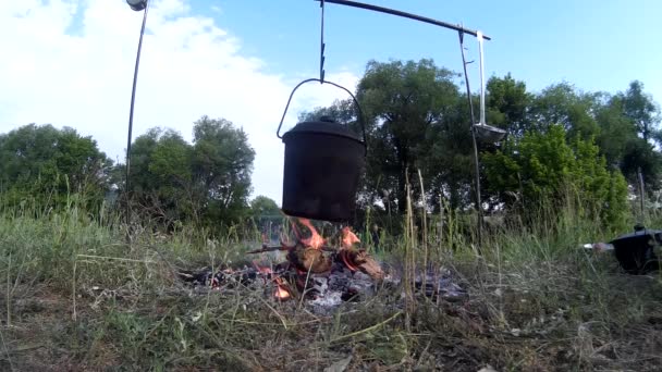 Cuisiner de la nourriture sur le feu de camp au bord de la rivière — Video