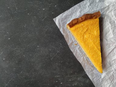 Beyaz buruşmuş kağıtta siyah bir parça balkabaklı cheesecake.