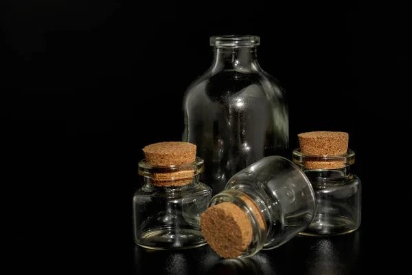Маленькие стеклянные бутылки с пробками на черном фоне — стоковое фото