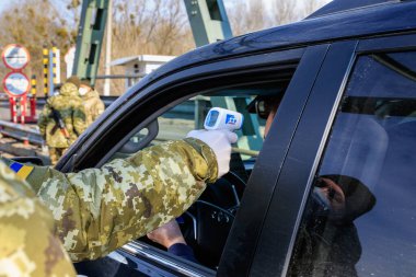 Chop, Ukrayna - 25 Şubat 2020: Sınır muhafızı Ukrayna sınır kapılarından geçen vatandaşların sıcaklık kontrolünü yapıyor. Ukrayna 'da Coronavirus koruması.