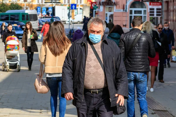 Uzhgorod, Ukrayna - 18 Mart 2020: Koronavirüs nedeniyle karantina sırasında tıbbi maskeli bir adam şehir merkezinde yürüyor.
