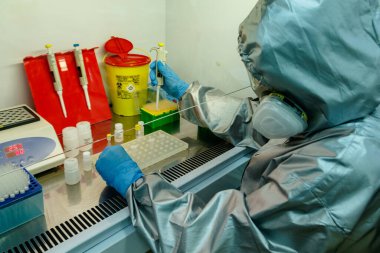 Uzhgorod, Ukrayna - 8 Mayıs 2020: Koruyucu giysi, maske ve gözlük giyen Epidemiyoloji uzmanı, laboratuvarda COVID-19 tanısını PCR yöntemi ile koydu.