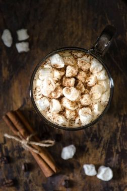 Bir fincan kahve ile krema ve tarçın. Koyu ahşap arka plan, üstten görünüm, dikey