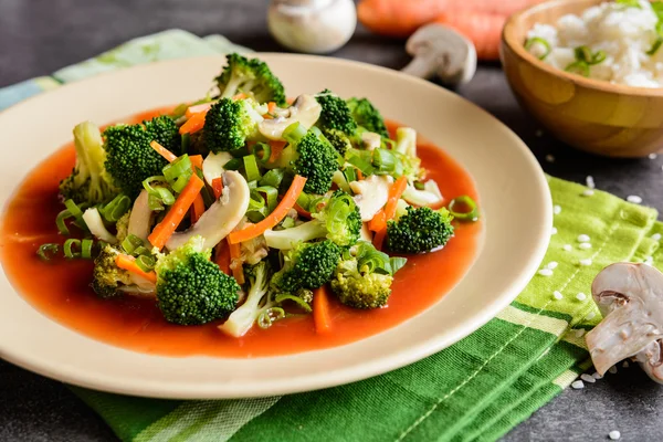 Broccoli aburit cu ciuperci, morcov și ceapă, servit cu sos de roșii și orez — Fotografie, imagine de stoc
