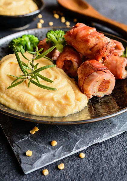 Geroosterde varkensschnitzel omwikkeld in spek en gevuld met worst, geserveerd met erwten puree — Stockfoto