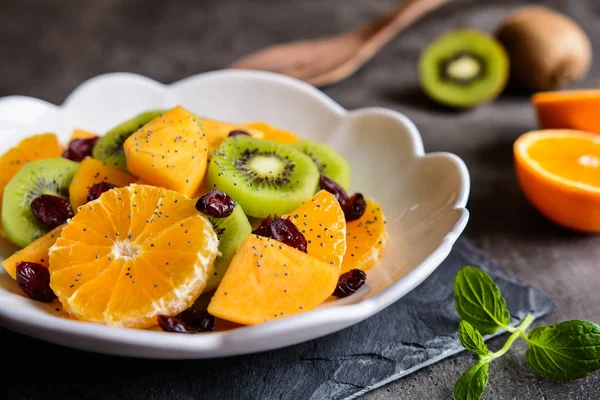 Fruktsallad med kiwi, persimoner, Minneola tangelo, tranbär, beströs med vallmofrön — Stockfoto