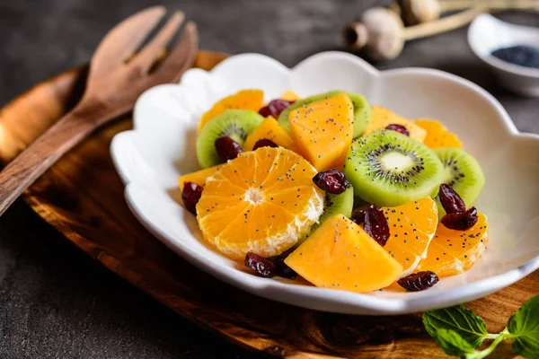 Fruktsallad med kiwi, persimoner, Minneola tangelo, tranbär, beströs med vallmofrön — Stockfoto