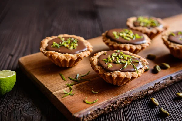 Tartlets with chocolate, pistachios and lime peel — Stock Photo, Image