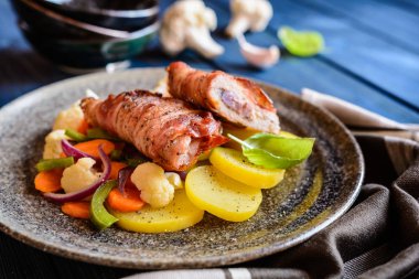 Kızarmış domuz pirzola pastırma sarılmış ve soğan ve hardal ile doldurulmuş, patates ile süslenmiş ve sebze buğulama