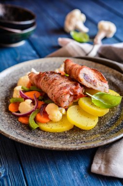 Kızarmış domuz pirzola pastırma sarılmış ve soğan ve hardal ile doldurulmuş, patates ile süslenmiş ve sebze buğulama