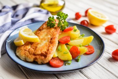 Fried fish fillets in batter, served with potato, tomato and scallion clipart
