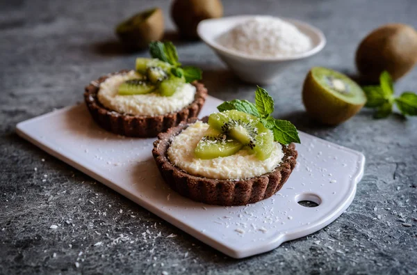 Çikolata tartlets Hindistan cevizi kreması ile dolu ve kivi dilimleri ile tepesinde
