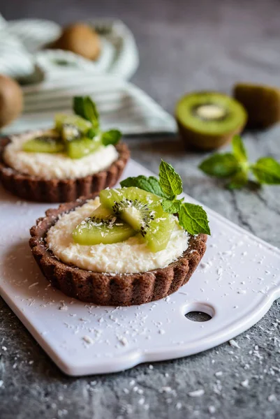 Çikolata tartlets Hindistan cevizi kreması ile dolu ve kivi dilimleri ile tepesinde