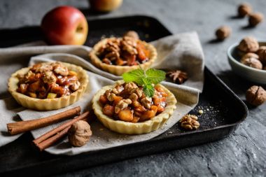 Karamelize elma parçaları, tarçın ve ceviz meyve tartlets dolu
