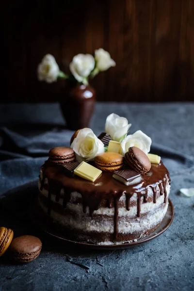 Tort gol umplut cu cremă de mascarpone, acoperit cu ciocolată și decorat cu flori, macaroane și bucăți de ciocolată — Fotografie, imagine de stoc