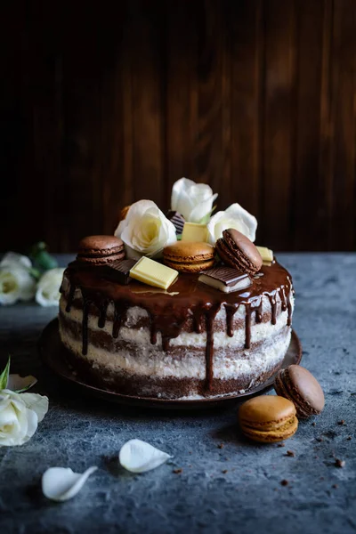Tort gol umplut cu cremă de mascarpone, acoperit cu ciocolată și decorat cu flori, macaroane și bucăți de ciocolată — Fotografie, imagine de stoc