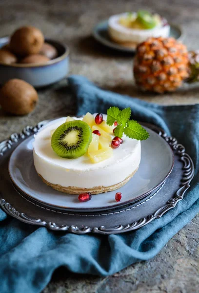 Unbaked mini cheesecakes topped with pineapple, kiwi and pomegranate — Stock Photo, Image