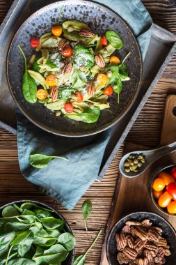 Ispanak, kırmızı ve portakal domatesli vejetaryen makarna salatası, kapari ve fındık fıstığı, üstüne dilimlenmiş peynir.