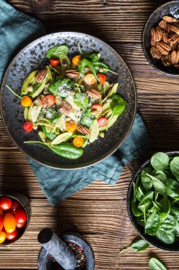 Ispanak, kırmızı ve portakal domatesli vejetaryen makarna salatası, kapari ve fındık fıstığı, üstüne dilimlenmiş peynir.