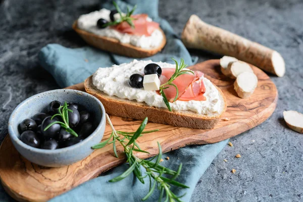 Felii de pâine cu răspândire cremoasă din brânză Feta, hrean și smântână, servite cu șuncă Schwarzwald și măsline negre — Fotografie, imagine de stoc