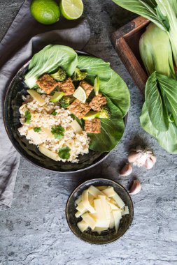 Pirinçli Tempeh, bok choy, buğulanmış brokoli ve bir tabakta bambu filizleri.