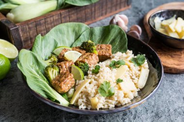 Pirinçli Tempeh, bok choy, buğulanmış brokoli ve bir tabakta bambu filizleri.