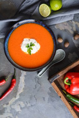 Kremalı kırmızı dolma biber çorbası ve seramik tabakta ekşi krema.