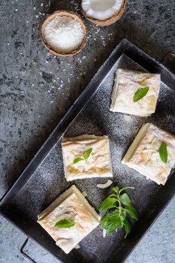 Vanilyalı ve hindistan cevizli kremalı tatlı, pudra şekerli.