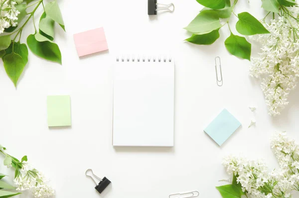 Top view of blank notebook and flowers on white workspace background. - Image