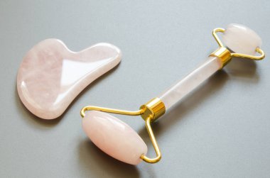 Gri arka planda pembe Gua Sha masaj aleti. Rose Quartz silindiri. Evde yüz bakımı, yaşlanmayı önleme ve kaldırma terapisi. - Görüntü