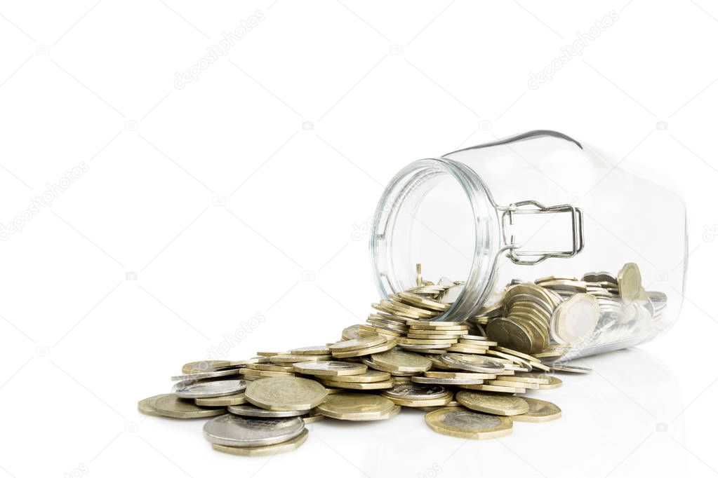 Overturned glass jar with golden and silver coins isolated on white background