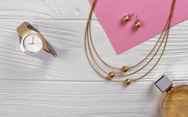 Reloj de oro y plata con collar de oro sobre fondo de madera blanca — Foto de Stock