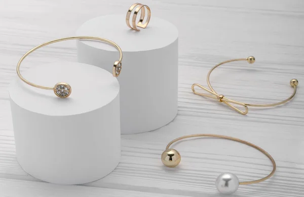 Коллекция браслетов Golden modern и кольцо на белых платформах на деревянном фоне — стоковое фото