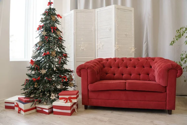Ozdobione choinki i pudełka prezentów z czerwoną sofą i drewnianą ścianą działową — Zdjęcie stockowe