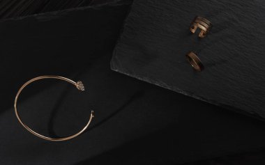 Elmas bilezikler ve altın yüzükler siyah taş tabaklarda