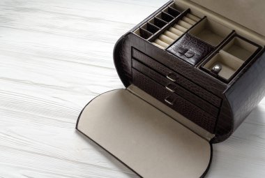 Beyaz ahşap masadaki boş kahverengi deri mücevher kutusunun üst görüntüsü.