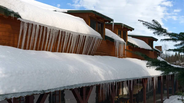 Carámbanos y nieve en la azotea de un edificio de madera en un día soleado en invierno — Foto de Stock