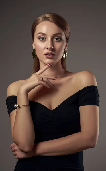 Vertical studio shot of pretty girl with natural tone make up wearing off shoulder black dress on grey background — 스톡 사진