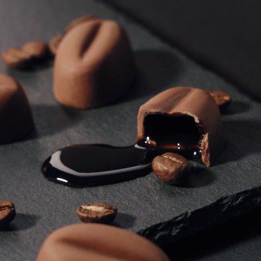 Kırık çikolata parçasından damlayan kahve likörü kaba taş yüzeyinde