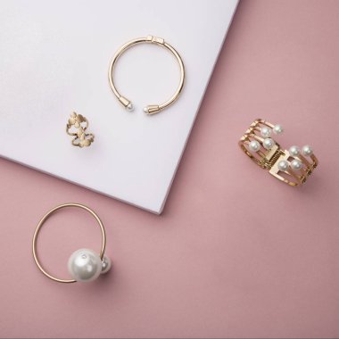 Pembe ve beyaz arka planda altın aksesuarların üst görünümü