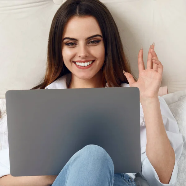 Casual Girl Macha Ręką Rozmowy Wideo Laptopie Leżąc Łóżku — Zdjęcie stockowe