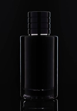 Siyah zemin üzerinde yansıması olan koyu cam parfüm şişesinin stüdyo fotoğrafı.