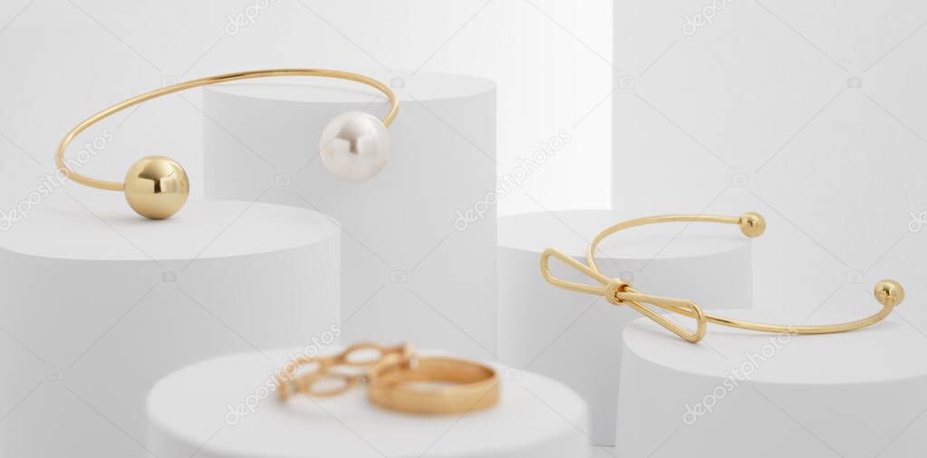 Modern golden bracelets with pearl on white cylinder blocks