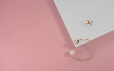 Pembe ve beyaz kağıt üzerinde altın bilezik ve yüzük manzarası