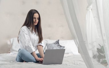 Ev konsepti üzerinde çalışıyorum. Evde, yatakta otururken bilgisayarla çalışan sıradan bir kız.