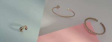 Parlak bilezikleri ve altın yüzüklü mavi ve pembe kağıtlı arka planı